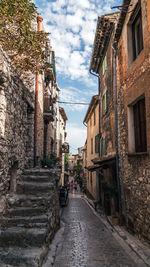 Walkway amidst buildings against sky