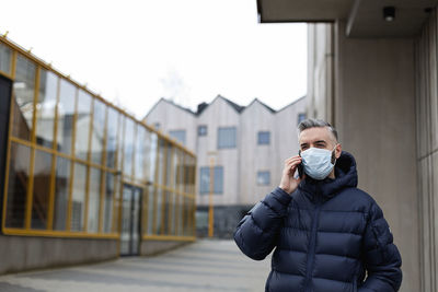 Man wearing face mask talking via cell phone