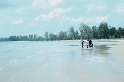 Friends wading in sea against sky