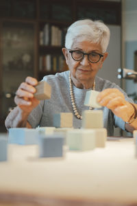 Smiling senior woman playing with toy blocks at home