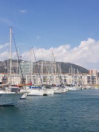 Sailboats moored in sea against sky