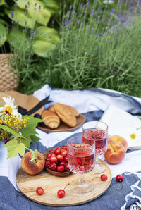 Picnic outdoors in lavender fields. rose wine in a glass, cherries and straw hat on blanket