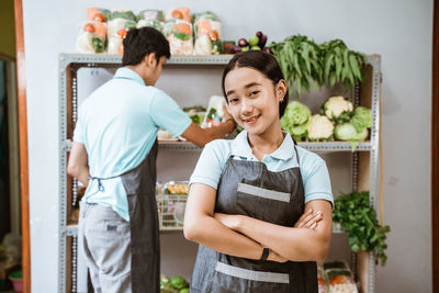 Portrait of smiling young woman standing against wall