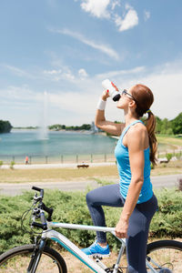 Woman riding bicycle against lake