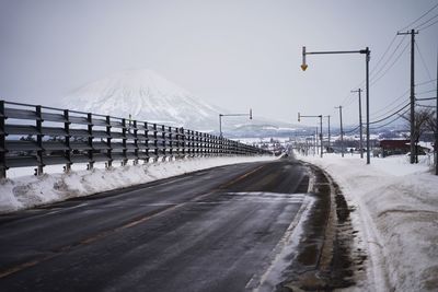 Road leading towards snow covered mountain against sky