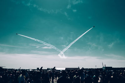 Airplanes flying over people against sky