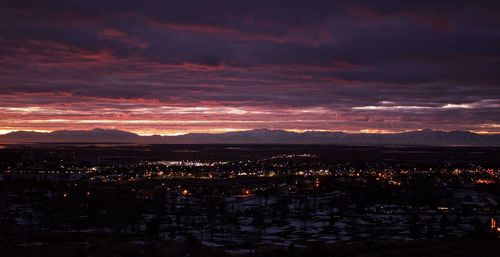 Aerial view of illuminated city against sky at sunset