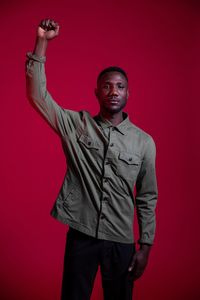 Portrait of young man standing against red background