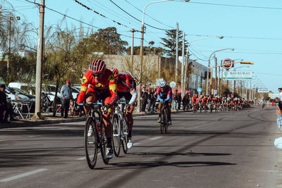 People riding bicycle on road against sky