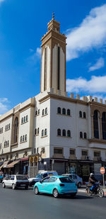 Cars on building against blue sky in city