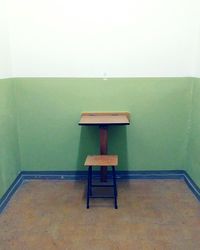 Empty chair on table against wall