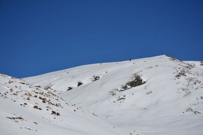 Low angle view of snowcapped mountain against clear blue sky