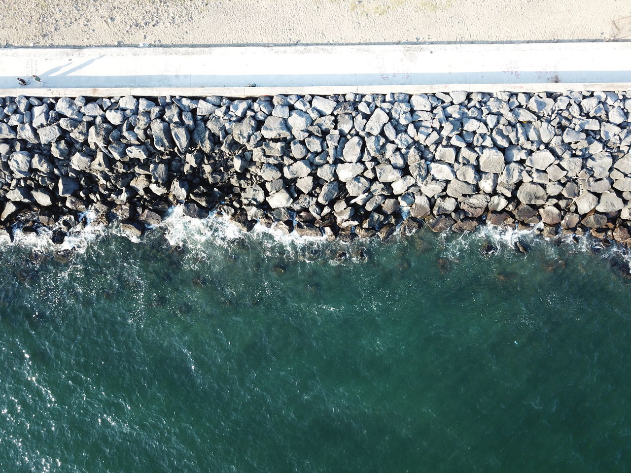 HIGH ANGLE VIEW OF STONES IN SEA