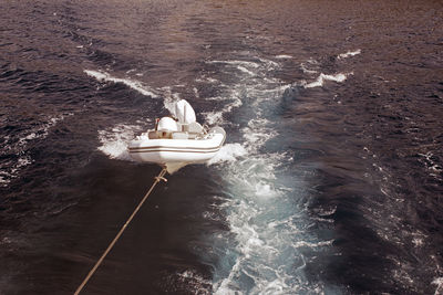 An inflatable boat pulled by a motorboat in the sea in summer