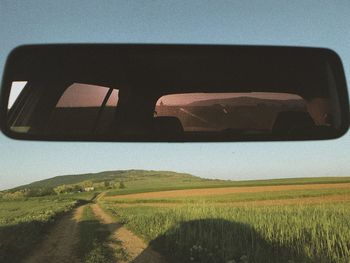 Tilt image of car on field against sky