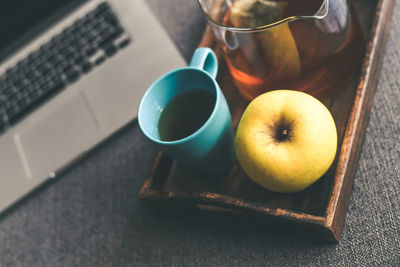 Close-up of laptop on table with coffee and apple