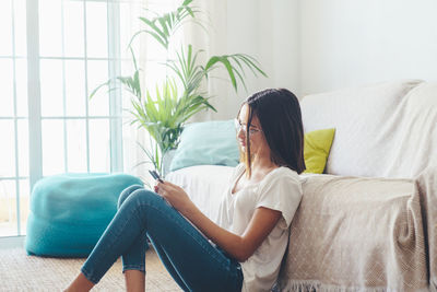 Young woman sitting on sofa at home