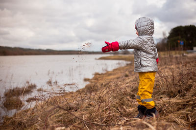 Side view of girl throwing rocks to the river on the riverside