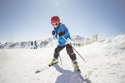 Full length of boy skiing on snow covered field against clear sky