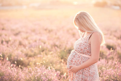 Smiling pregnant woman standing on field