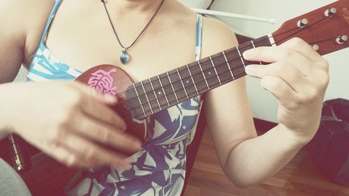 Midsection of woman playing ukulele