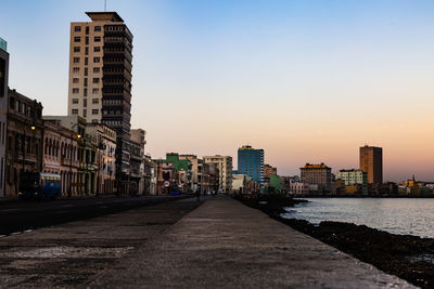 Buildings by sea against sky during sunset