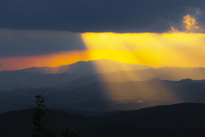 Scenic view of silhouette mountains against orange sky