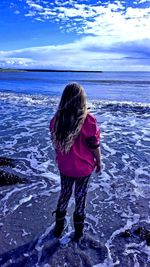 Rear view of woman standing in sea against sky