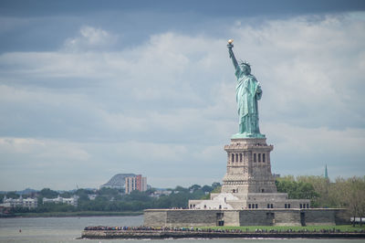 Statue of liberty against cloudy sky in city