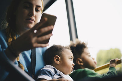 Mother using mobile phone while sitting with son in bus