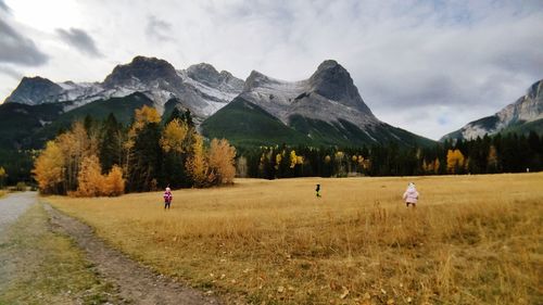 Girls playing on grassy field against mountain