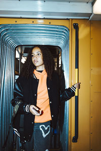 Teenage girl standing at doorway of tram while traveling during weekend