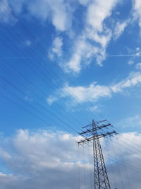 Low angle view of electricity pylon against blue sky