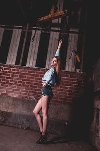 Female model posing against wall at night