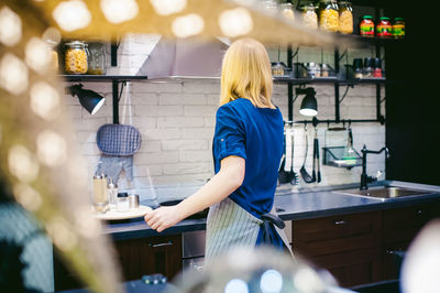 Rear view of woman making food in kitchen at home