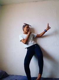 Teenage girl standing against wall