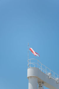 Low angle view of flags against clear blue sky