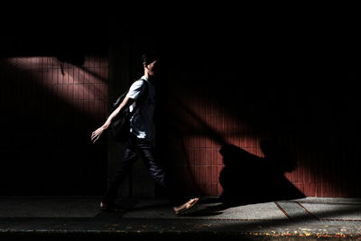 Side view of man walking on footpath at night