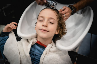 High angle view of boy getting hair wash at hair salon