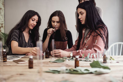 Female colleagues preparing perfume pipette at table in workshop