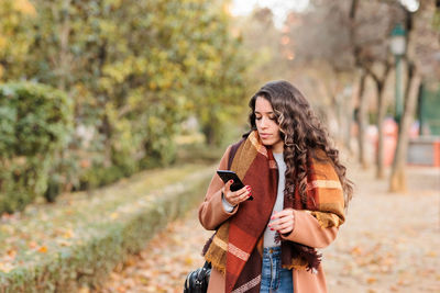 Side view of young woman using mobile phone