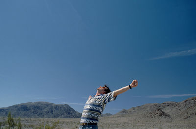 Man with arms raised against clear sky