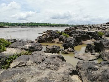 Scenic view of rocks on shore against sky