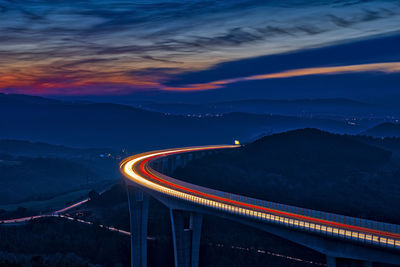 Light trails on road against sky at night