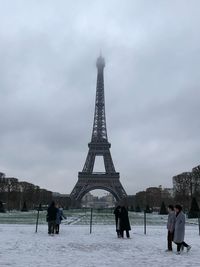 People on snow covered tower in city against sky