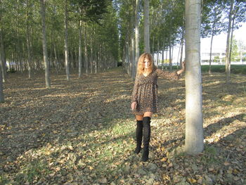 Woman standing by tree trunk in forest