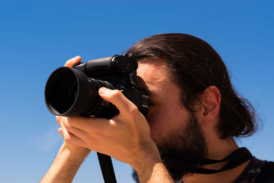 Portrait of man photographing against sky