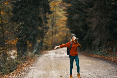 Full length of woman standing on road in forest