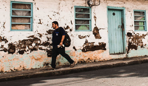 Full length of man running on street against building