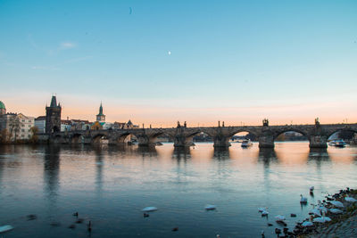 Bridge over river in city against clear sky